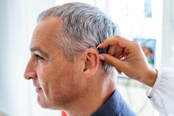A mature man receiving a hearing aid fitting