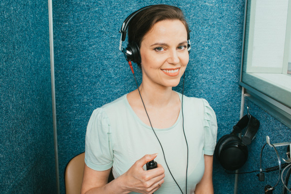 An adult woman receiving a hearing test in the testing booth